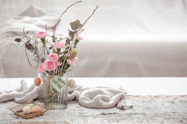 Vazoda taze çiçeklerle dolu bir hayat ve bulanık bir arka planda neşeli Paskalya dekorunun ayrıntıları..