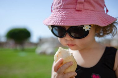 Komik küçük kız yazın bahçede egzotik meyveler yiyor..