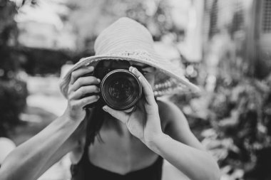 Sıcak bir yaz gününde, şapkalı genç bir kadın profesyonel bir SLR kamerasıyla fotoğraf çekiyor..