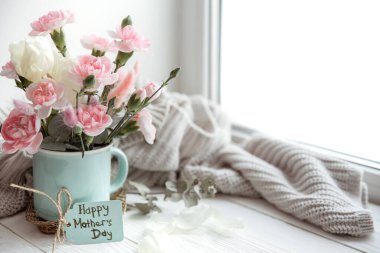 Vazoda çiçeklerle dolu bir bahar ve kartpostalda Anneler Günü 'nün kutlu olsun yazısıyla..