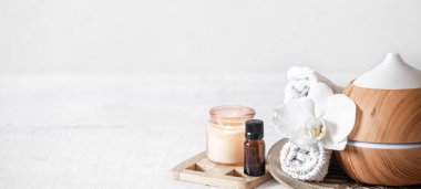 Hava nemlendiricisini, havluyu, aromatik yağı ve orkide çiçeğini kapatın. Aromaterapi ve bakım ve sağlık konsepti.