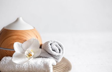 Hava nemlendiricisini, havluyu ve orkide çiçeğini kapatın. Aromaterapi ve bakım ve sağlık konsepti.