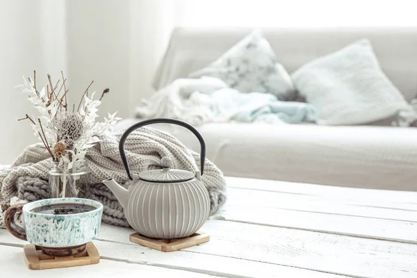 Bir çaydanlık ve içinde dekorasyon detayları olan seramik bir kupa Hygge tarzı oturma odasında. Ev konforu ve modern tarz kavramı.
