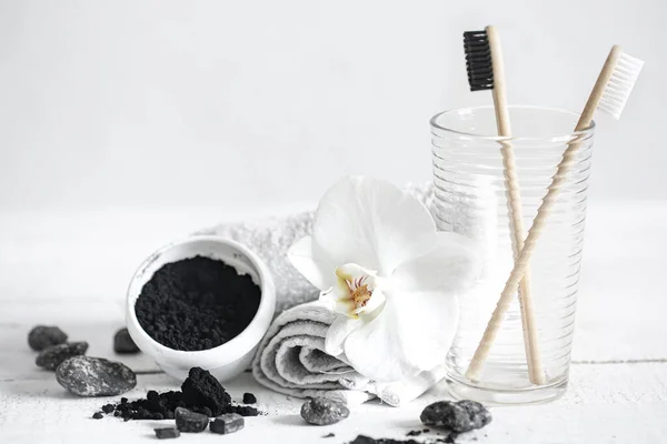 Still life with organic bamboo brushes and activated carbon powder and an orchid flower as a decorative element. Oral hygiene and dental care.