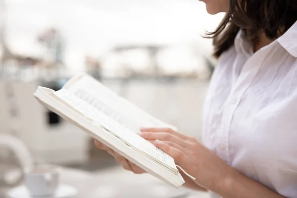 Close up of a book in female hands on a blurred background.