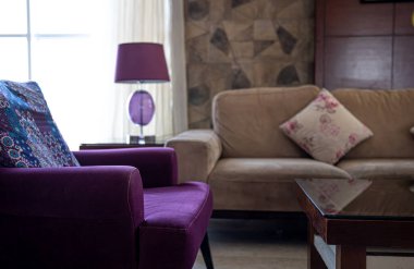 Oturma odasının içinde rahat koltuklar, masa lambası ve pencerenin yanında yer lambası var. Oturma odası tasarımı fikri.