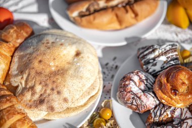 Kahvaltı masasında kruvasan, çörek ve tortilla var..