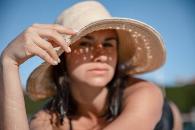 Güneşli bir günde hasır şapka takan baştan çıkarıcı genç bir kadın. Tatil ve yaz konsepti.