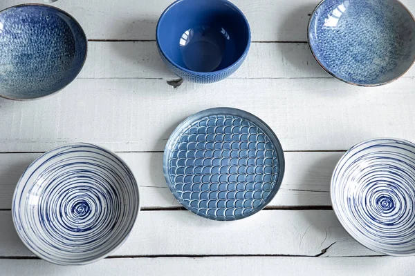 Empty ceramic tableware. Ceramic plates on wooden surface. Overview empty food table with tableware. Set of different modern blue plates.