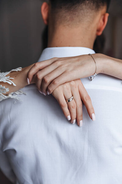 The groom in the arms of his bride, view from the back. Wedding photo session.