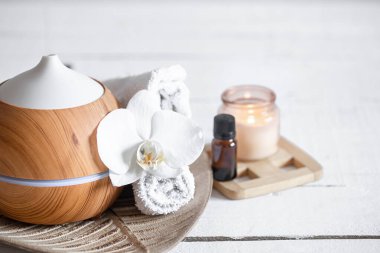 Hava nemlendiricisini, havluyu, aromatik yağı ve orkide çiçeğini kapatın. Aromaterapi ve bakım ve sağlık konsepti.