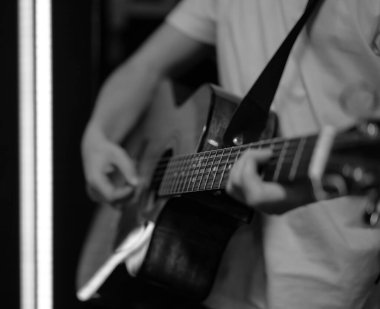 Bir adam karanlık bir odada akustik gitar çalar. Canlı performans, akustik konser, prova..