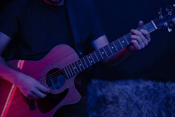 A man plays an acoustic guitar in a dark room copy space. Live performance, acoustic concert.
