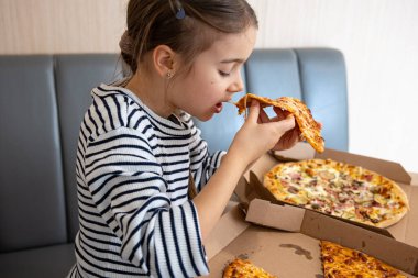 Küçük kız öğle yemeğinde iştah açıcı peynirli pizza yiyor. Lezzetli peynirli pizza..