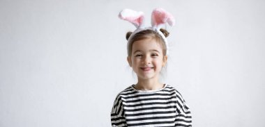 Kafasında süslü Paskalya tavşanı kulakları olan neşeli küçük bir kız..