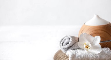 Hava nemlendiricisini, havluyu ve orkide çiçeğini kapatın. Aromaterapi ve bakım ve sağlık konsepti.