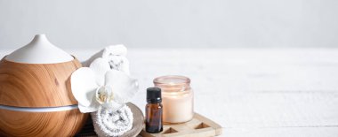 Hava nemlendiricisini, havluyu, aromatik yağı ve orkide çiçeğini kapatın. Aromaterapi ve bakım ve sağlık konsepti.