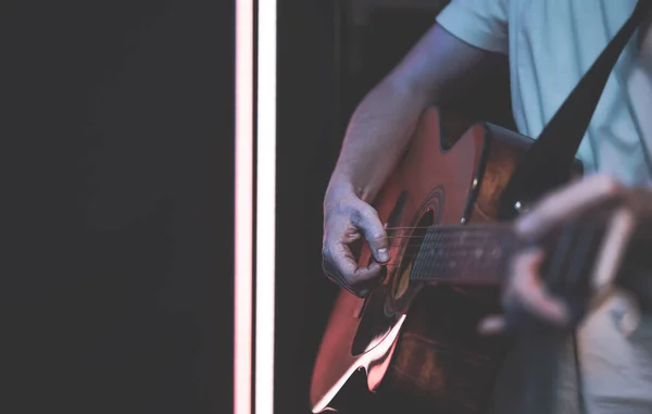 A man plays an acoustic guitar in a room copy space. Live performance, acoustic concert, practice.