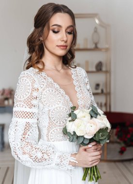 Elinde bir buket taze çiçek ve dantelli güzel bir şenlik elbisesi olan gelin. Düğün fotoğrafı, gelin sabahı..