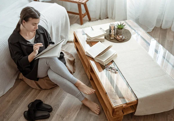 Uma Jovem Estudante Faz Tarefas Casa Sentada Com Caderno Nas — Fotografia de Stock