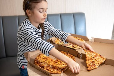 Küçük kız öğle yemeğinde iştah açıcı peynirli pizza yiyor. Lezzetli peynirli pizza..