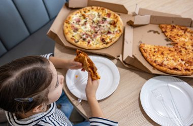 Küçük kız öğle yemeğinde iştah açıcı peynirli pizza yiyor. Lezzetli peynirli pizza..