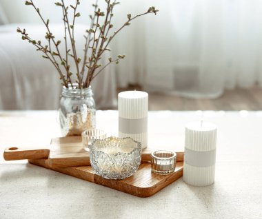 Odanın içinde mumlar olan bir vazoda genç dallarla bahar kompozisyonu.