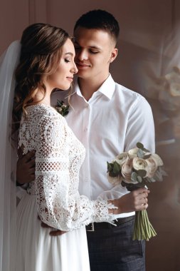 Damat güzel bir gelinlik içinde geline nazikçe sarılır. Yeni evlilerin düğün fotoğrafları..