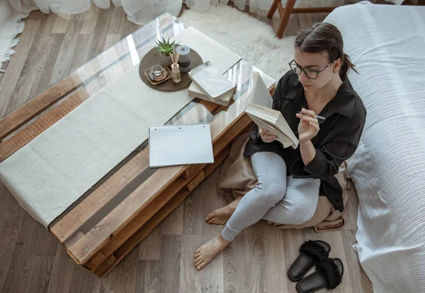 Attraktives Mädchen Mit Brille Liest Hause Auf Einem Hocker Sitzend — Stockfoto