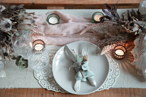 Romantic table setting with burning candles and dried flowers for a wedding or Valentine's Day.