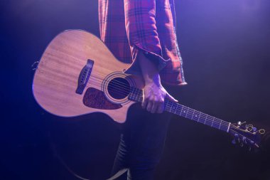 Elinde akustik gitar tutan bir adam yakına geliyor..