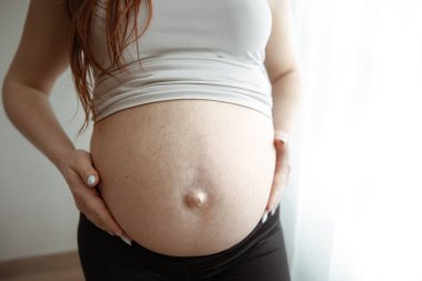 Hamileliğin son aylarında hamile olan annenin çıplak karnının yakın çekimi..