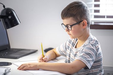 Bir ilkokul öğrencisi ödevini kendi başına yapar..