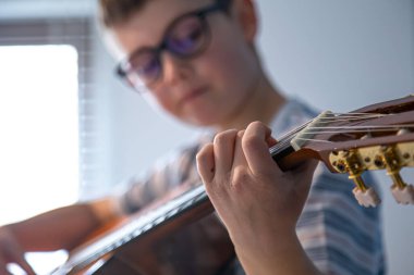 Gitar çalan bir çocuğun elinin yakın çekimi..