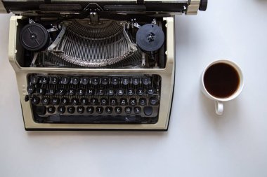 Masanın üstünde eski moda daktilo ve bir fincan sade kahve..