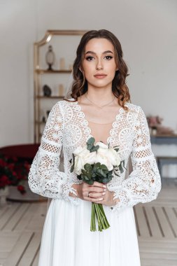 Elinde bir buket taze çiçek ve dantelli güzel bir şenlik elbisesi olan gelin. Düğün fotoğrafı, gelin sabahı..