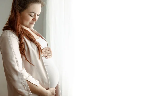 怀孕最后几个月的时髦孕妇站在窗前 — 图库照片