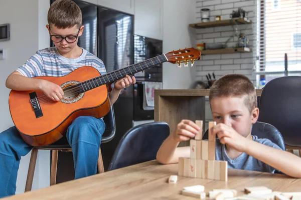 Niño Toca Guitarra Hermano Construye Una Torreta Con Cubos Madera — Foto de Stock