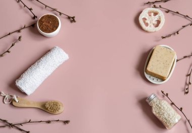 Bahar ağacı dalları arasında sabun, fırça, lif, deniz tuzu ve havlu içeren spa kompozisyonu.