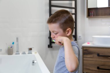 Hoş, küçük bir çocuk sıcacık bir banyoda dişlerini fırçalıyor..