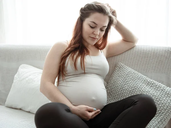 肚子大的准妈妈正坐在家里的沙发上 — 图库照片