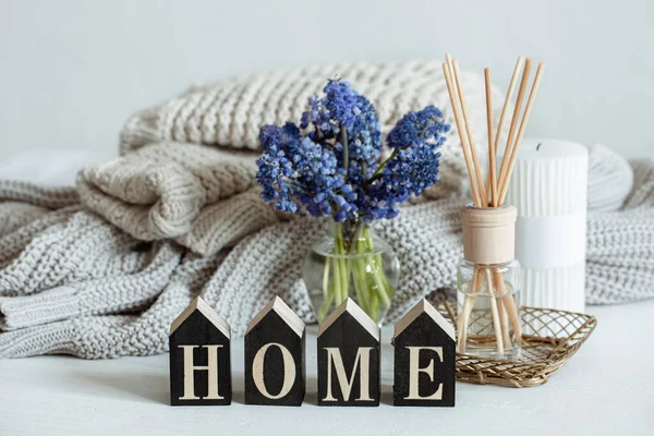 Spring home composition with flowers, aroma sticks, knitted element and decorative word home.