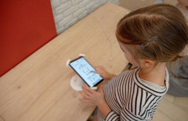 Alet dükkanındaki küçük bir kız telefonu inceliyor. Bir çocuk için yeni bir akıllı telefon seçmek.