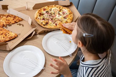 Küçük kız öğle yemeğinde iştah açıcı peynirli pizza yiyor. Lezzetli peynirli pizza..