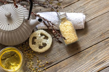 Ahşap bir yüzey üzerinde çaydanlık, çay ve lif ile kırsal tarzda spa kompozisyonu.