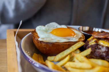 Kızarmış yumurtanın bir tabakta bir hamburgerin yarısının üzerinde yakın plan..