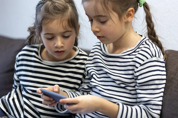 Słodkie Małe Siostry Używać Telefonów Siedząc Kanapie Domu — Zdjęcie stockowe