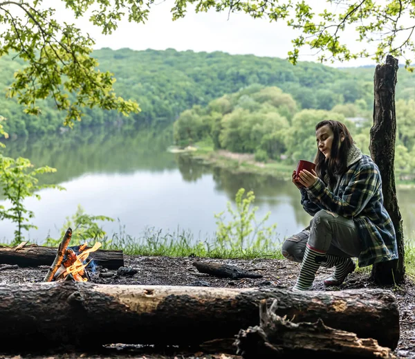 Young Woman Forest River Warms Fire Drinks Hot Drink — Stock Photo, Image