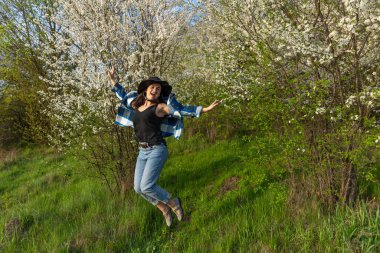 Bahar ormanında yürüyüş yapan çekici bir kız. Sıradan bir şekilde atlıyor..