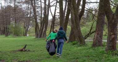 İlkbaharda, ormanın çıkışındaki çöpü temizleyen bir kızın arkasından..
